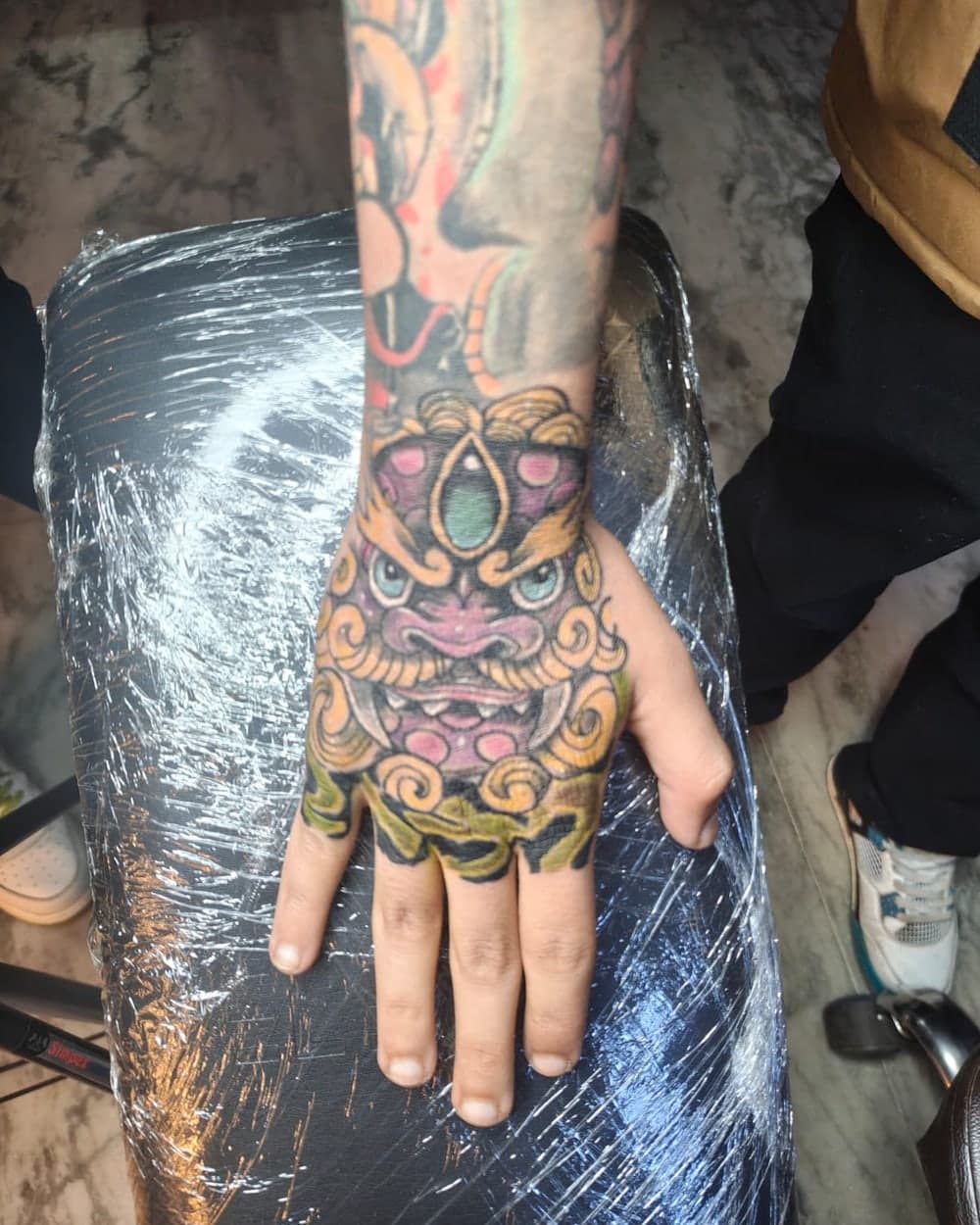 Colour foo dog hand tattoo with bold outlines